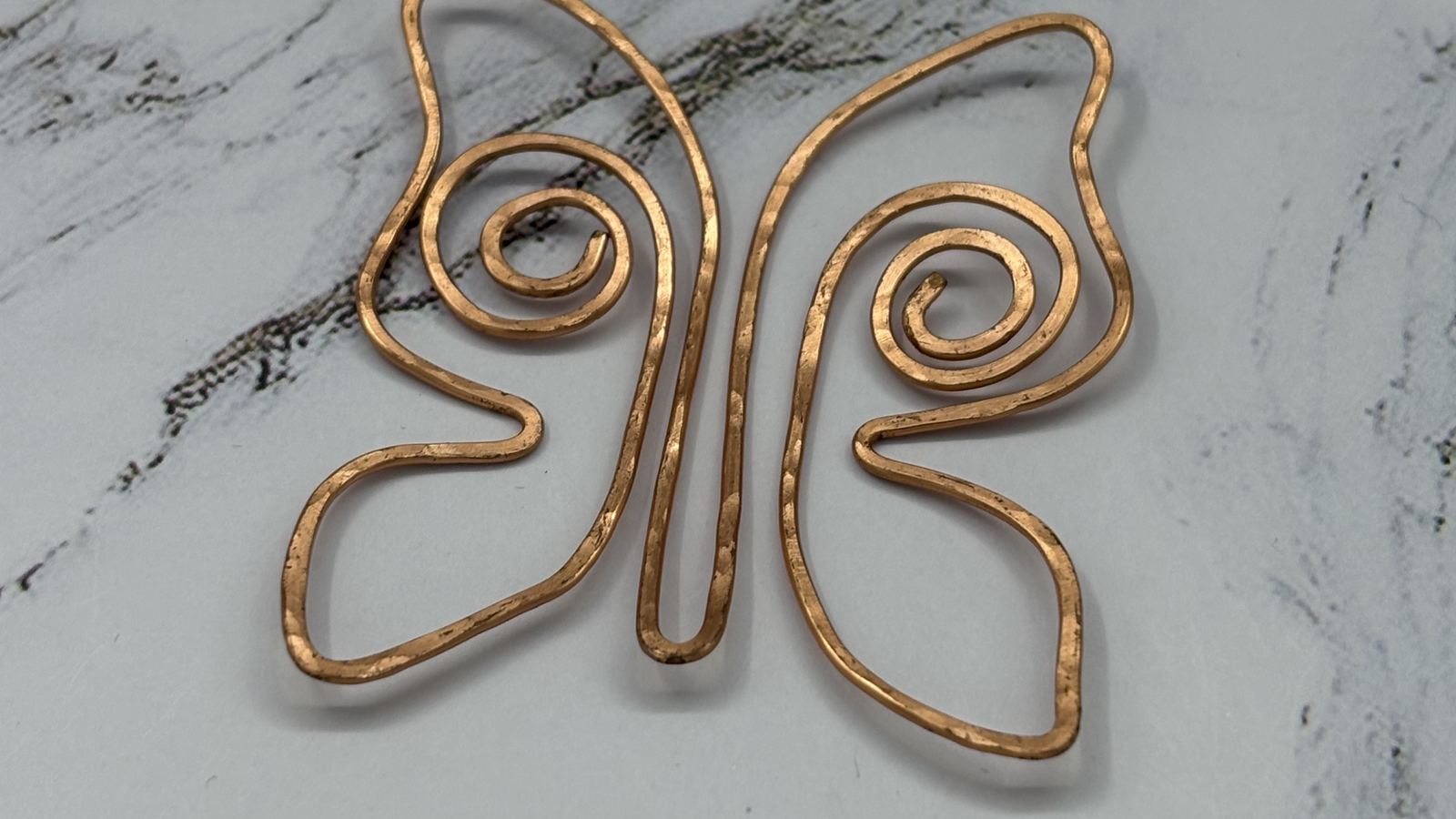 Hammered copper butterfly bookmark on marble