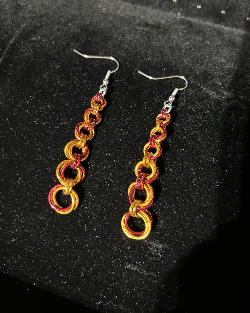Custom orange and red chainmaille drop earrings on black velvet